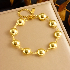 Polished gold stainless steel link bracelet with oval beads on jewelry display