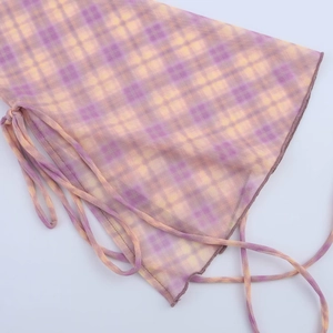 Détail du tissu en maille transparente avec motif à carreaux violet et jaune et lien