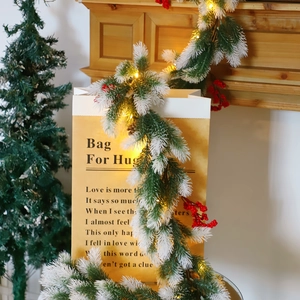 Close-up of Christmas pine needle garland with red berries and LED lights on a paper bag