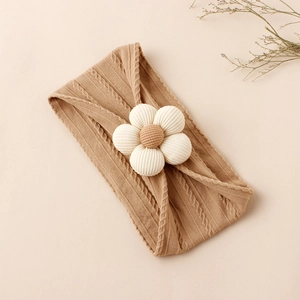 Detail showing the cable knit texture and 3D floral accent on a soft nylon baby headband