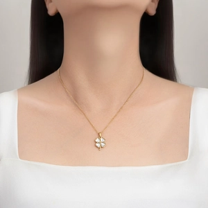 Élégant collier en acier inoxydable doré avec pendentif trèfle blanc porté par un mannequin