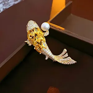 Spilla carpa koi placcata in oro con gemme gialle e un dettaglio di perla bianca