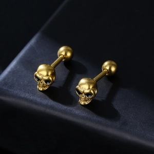 Gothic gold skull stud earrings for men in polished stainless steel on black background
