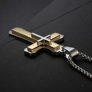 Gros plan d'un pendentif croix double couche en acier doré et argenté avec chaîne