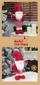 Detail of red and white knitted Christmas gnome holding a candy cane by a warm fireplace