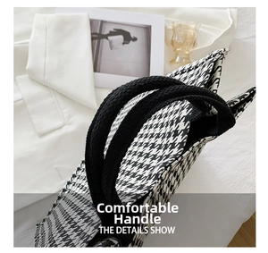 Detail of black and white houndstooth tote bag with comfortable woven handles on soft fabric
