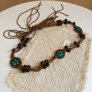 Detail of bohemian woven brown belt with blue gemstones, bronze discs and tassels