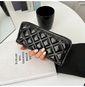 Close-up of black patent leather long wallet with diamond quilted stitching and metallic studs