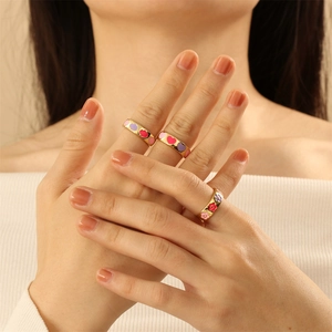 Close-up of three gold-plated enamel rings with colorful heart, cloud and flower patterns