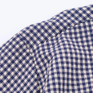 Détail du tissu seersucker à carreaux bleus et blancs montrant les coutures de l'épaule