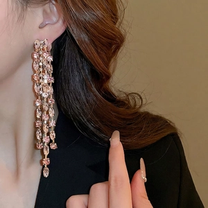 Elegant gold-tone tassel earrings with pink oval crystals shown on a fashion model