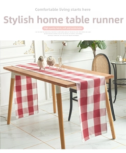 Detail of red and white plaid Christmas table runner on a rustic wooden dining table