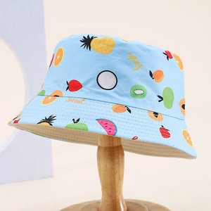 Light blue kids sun hat with colorful fruit prints on a minimal wooden stand