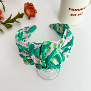 Detail of wide knotted headband with green and pink floral pattern on satin fabric