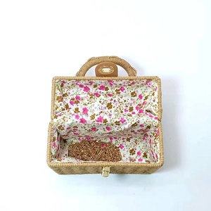 Top view of woven box bag interior with floral lining and golden chain strap