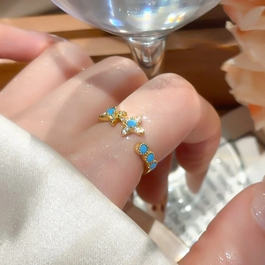 Detailed view of 18k gold star ring with blue stones and crystals on a model hand