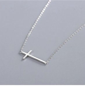 Detailed macro view of a polished silver horizontal cross pendant on a thin link chain