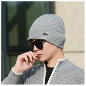 Detail of grey ribbed knit beanie with stylish metal logo plate for men