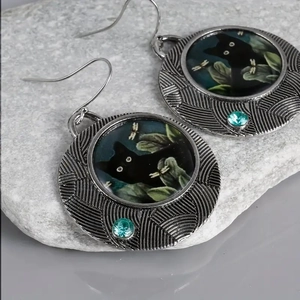 Detail of vintage silver alloy cat earrings featuring green gemstones on grey stone base