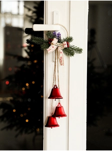 Detail of red Christmas bells with pine needles and Merry Christmas ribbon on door