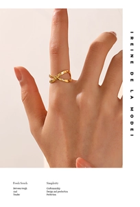 Close-up of golden crossover ring with a hammered texture finish on a model's hand