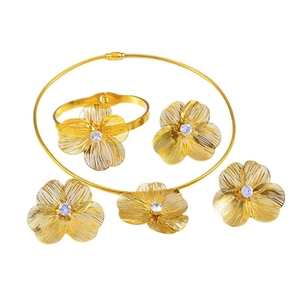 Golden flower jewelry set with hollow petal textures and blue zircon stones on white background