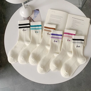 Detailed view of white knitted athletic socks with colorful stripes and Smile embroidery