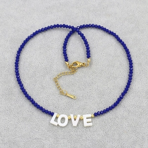 Detail of dark blue beaded necklace with white LOVE letter beads and golden clasp