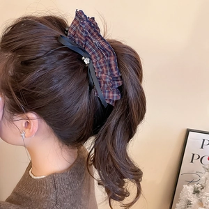 Detail of red and blue checkered bow hair clip with black ribbon and metal flower charm