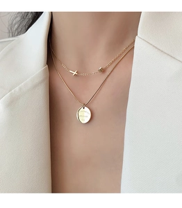 Detail of 18K gold double layer necklace with cross and engraved round pendant