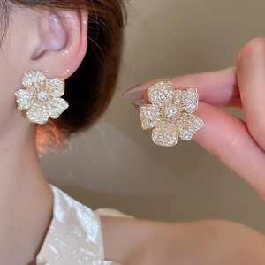 Detail showing elegant gold five-petal flower earrings with micro-set zircon stones
