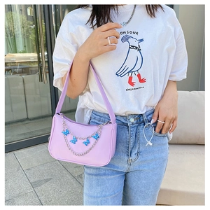 Detailed view of lavender shoulder bag featuring silver chain and blue butterfly charms