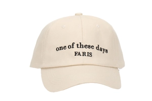 Detail of black letter embroidery on cream cotton baseball cap with curved brim