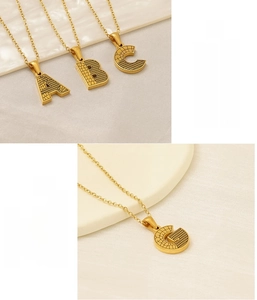 Gros plan du pendentif lettre G en acier inoxydable doré avec texture crocodile