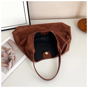 Detailed interior of brown faux suede tote bag showing magnetic buckle and black lining