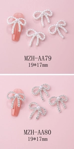 Detailed view of silver bow nail charms with pearls and crystals on pink background