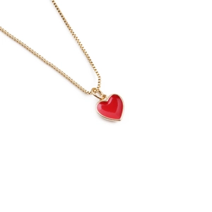 Macro detail of red heart-shaped pendant with gold-plated trim on a fine link chain