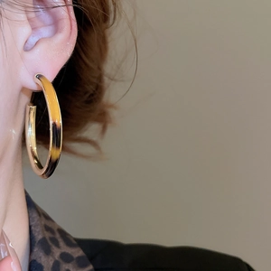 Close-up of model wearing gold and tortoiseshell acetate C-shaped hoop earrings