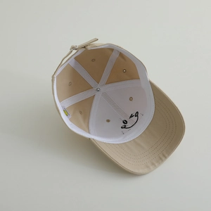 Detailed interior of kids beige baseball cap with smiley print and adjustable buckle