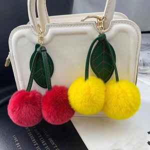 Cute cherry pompom keychain in red and yellow fur with leather leaves for handbags