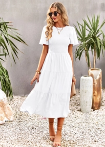 Detail of white round neck summer dress with smocked bodice and layered skirt