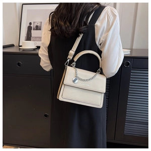 Detail of off-white PU leather crossbody bag with silver chain and fashion metal tag