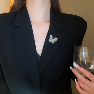 Detailed view of a silver butterfly brooch with teardrop zircons on a black blazer