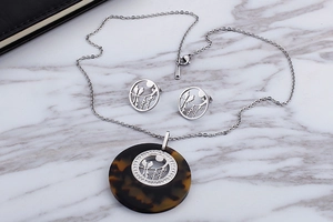 Close-up of stainless steel jewelry set with flower-bird patterns and resin texture