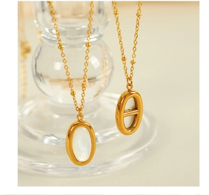 Macro detail of gold necklaces with white shell pendant and hollow oval link design