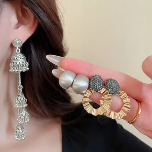 Set of retro silver tassel bells and gold diamond hoop earrings for women on a model