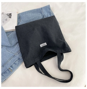 Thick black canvas tote bag with fashion label styled with denim jacket and book
