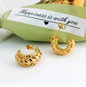 Detailed view of gold twisted U-shaped hoop earrings with a high-polished braided texture