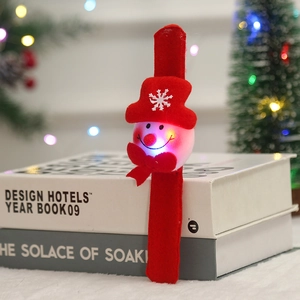 Glow-in-the-dark red snowman Christmas bracelet with LED light standing on a white book