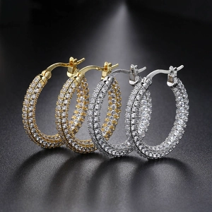 Sparkly multi-row rhinestone hoop earrings in gold and silver finish on black background